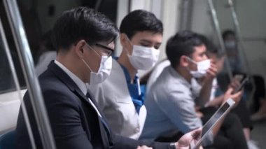 İş adamı akıllı tablet kullanıyor ve metro metrosunda maske takan bir kadınla buluşuyor. Salgın Grip Coronavirüsü ya da covid 19 ile yeni bir yaşam kavramı.