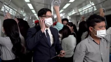 Yüz maskeli iş adamı akıllı tablet cihazlar kullanıyor ve metro metrosunda toplu taşıma araçlarıyla seyahat eden insanlarla birlikte duruyor. Salgın Hastalıklı Corona Virüsü ile yeni bir normal yaşam.