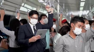 Yüz maskeli iş adamı akıllı tablet cihazlar kullanıyor ve metro metrosunda toplu taşıma araçlarıyla seyahat eden insanlarla birlikte duruyor. Salgın Hastalıklı Corona Virüsü ile yeni bir normal yaşam.
