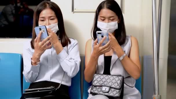 Asiatinnen Mit Gesichtsmaske Sitzen Der Bahn Und Checken Mit Dem — Stockvideo