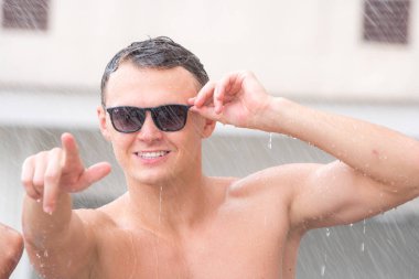 Siyah gözlüklü beyaz adamın vücudundaki kasların portresi dans ediyor..