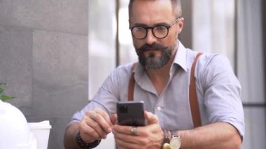 Üst düzey bir adam açık kafede akıllı telefon kullanıyor..