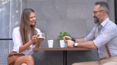 Üst düzey bir adam ve kadın açık bir kafede kahve içerken konuşuyorlar. Pastayı adama gösteren kadın onu görünce şaşırdı..