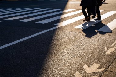 Silüet üst görünümü insanlar yaya yaya yaya geçidinde yürüyorlar akşam gün batımında caddede karanlık bir gölgeyle.