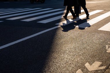 Silüet üst görünümü insanlar yaya yaya yaya geçidinde yürüyorlar akşam gün batımında caddede karanlık bir gölgeyle.