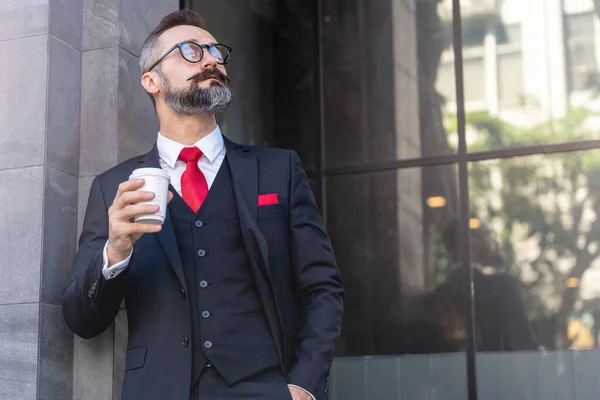 man in business suit holding cup of coffee. business lifestyle in coffee time at morning daylight.man feeling fresh and happy with confident of success.
