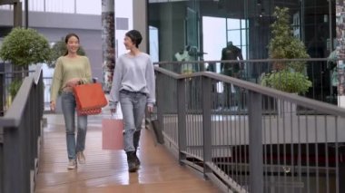Güzel genç Asyalı kadınlar birlikte alışveriş yapıyorlar.