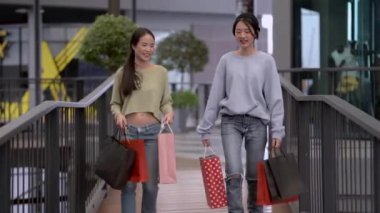 Güzel genç Asyalı kadınlar birlikte alışveriş yapıyorlar.