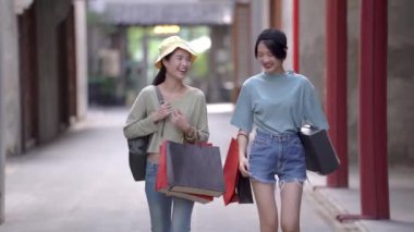 Güzel genç Asyalı kadınlar birlikte alışveriş yapıyorlar.