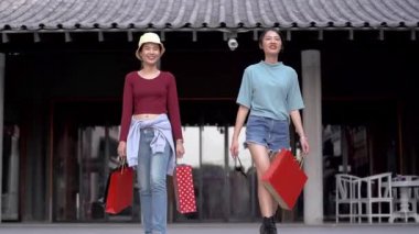 Güzel genç Asyalı kadınlar birlikte alışveriş yapıyorlar.