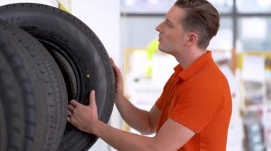 Otomobil servisi çalışanları kapalı ambardaki lastik stoklarını kontrol ediyor. Yedek parça taşımacılığının endüstriyel deposunda çalışan insanları düşünün.