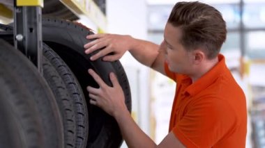 Otomobil servisi çalışanları kapalı ambardaki lastik stoklarını kontrol ediyor. Yedek parça taşımacılığının endüstriyel deposunda çalışan insanları düşünün.