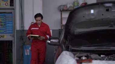 Fabrika elbiseli işçiler garaj otoparkındaki araba motoruna doğru yürüyorlar. Yedek parça taşımacılığının endüstriyel deposunda çalışanlar.