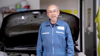 Garaj otoparkındaki araba aküsünü gösteren fabrika elbiseli üst düzey işçi personeli. Yedek parça taşımacılığının endüstriyel deposunda çalışanlar.