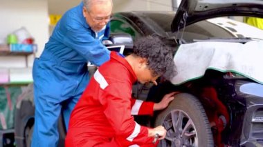 İşçiler ve fabrika çalışanları araba tekerleğini tamir ediyor ve garaj otoparkını yoruyor. Yedek parça taşımacılığının endüstriyel deposunda çalışanlar.