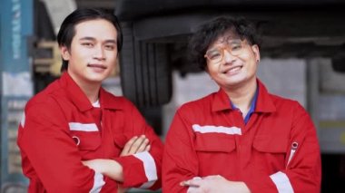 Otomobil servisinde çalışan işçilerin portresi kapalı deponun ön tekerlek stokunda duruyor. Yedek parça taşımacılığının endüstriyel deposunda çalışan insanları düşünün.