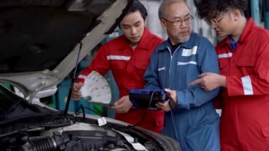 Fabrika elbiseli işçiler ve kıdemli çalışanlar bir araba motoru tamir ediyorlar bir garaj otoparkı. Yedek parça taşımacılığının endüstriyel deposunda çalışanlar.