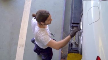 Fabrika elbiseli, araba tamircisi ve garaj otoparkını tamir eden işçilerin üst düzey görüntüsü. Yedek parça taşımacılığının endüstriyel deposunda çalışanlar.