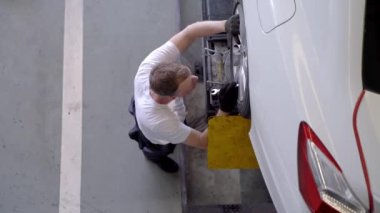 Fabrika elbiseli, araba tamircisi ve garaj otoparkını tamir eden işçilerin üst düzey görüntüsü. Yedek parça taşımacılığının endüstriyel deposunda çalışanlar.