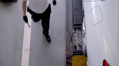 Fabrika elbiseli, araba tamircisi ve garaj otoparkını tamir eden işçilerin üst düzey görüntüsü. Yedek parça taşımacılığının endüstriyel deposunda çalışanlar.