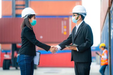 Erkek kadın mühendislerin ve işçilerin portresi konteynır ve kargo alanının önünde el sıkışıyor ve buluşuyorlar. Nakliye sektöründe çalışan kendinden emin ve zeki iş adamları..