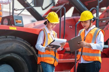 Erkek kadın mühendislerin ve işçilerin portresi. Ağır makineli aracın önünde toplanıp teftiş ediyorlar. Nakliye sektöründe çalışan kendinden emin ve zeki iş adamları..