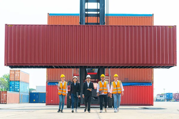 Portrait Of man woman Engineers and asian Factory workers walking in front of machine lift container and cargo space. Business people with confident and smart working in shipping transport industry.