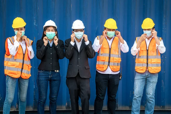 group people worker is wearing protection mask face and safety helmet and wearing suit safety dress With background cargo warehouse. industry worker operating.