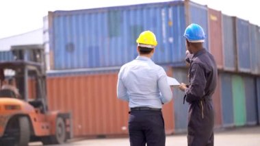 Factory worker holding laptop and talking with businessmen engineer. At container shipping area Foreman control and manager looking around. Business man onsite workplace inspecting.