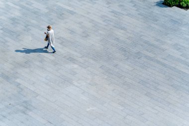 Üst düzey hava manzaralı insanlar yaya betonunda yürüyorlar. Yerde siyah gölgeler, sosyal durağan yaşam kavramı.