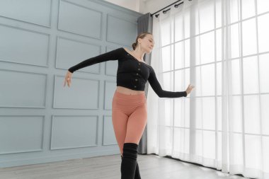 Stüdyodaki kadın balerin portresi. Çağdaş dans sanatçısı. Klasik bale eğitimi aldım. Güzel zarif balerin duvar ve pencere lambasında bale pratiği yapıyor..