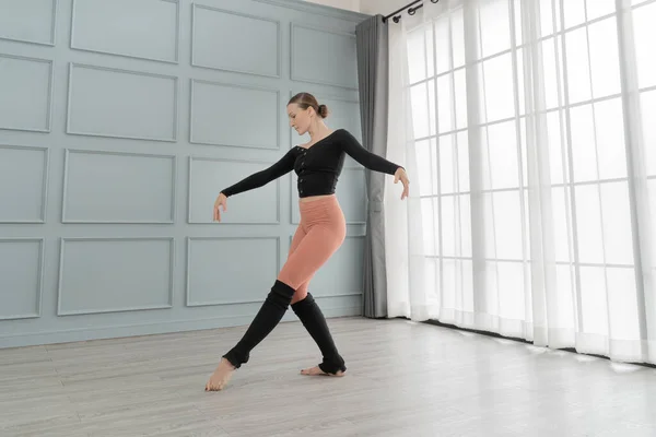 portrait of woman ballet dancer perform in studio house. Contemporary dance performer. Classical Ballet dancer training. Beautiful graceful ballerina practice ballet at wall and window light hall.