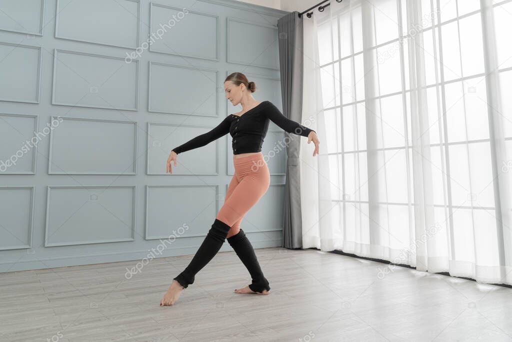 portrait of woman ballet dancer perform in studio house. Contemporary dance performer. Classical Ballet dancer training. Beautiful graceful ballerina practice ballet at wall and window light hall.