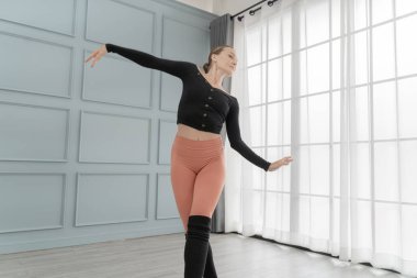 Stüdyodaki kadın balerin portresi. Çağdaş dans sanatçısı. Klasik bale eğitimi aldım. Güzel zarif balerin duvar ve pencere lambasında bale pratiği yapıyor..