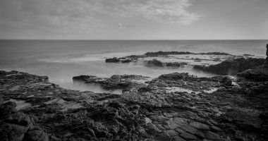 Uzun pozlama siyah beyaz kayalık sahil.