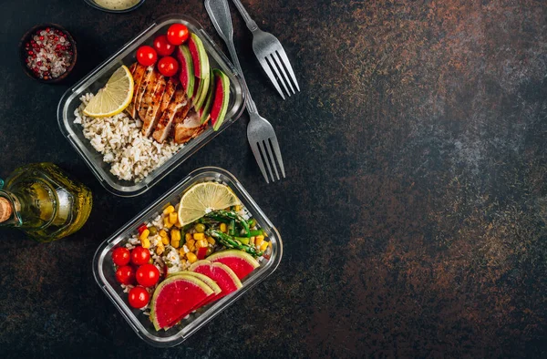 Healthy meal prep containers with chicken, rice, avocado, tomato, corn, peas, watermelon radish, asparagus on dark background. Top view