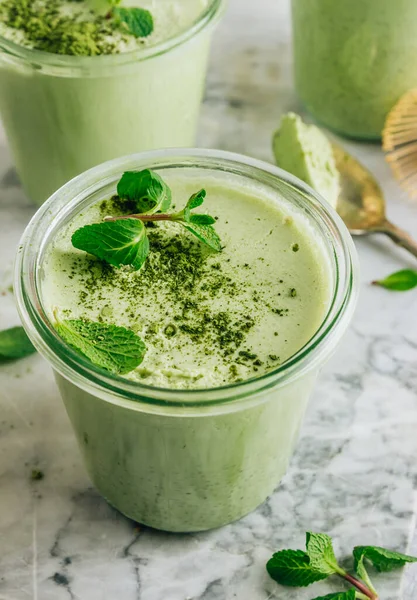 Raw vegan dessert. Matcha green tea chia seed pudding with fresh mint and coconut milk on a gray stone background. Healthy breakfast Selective focus