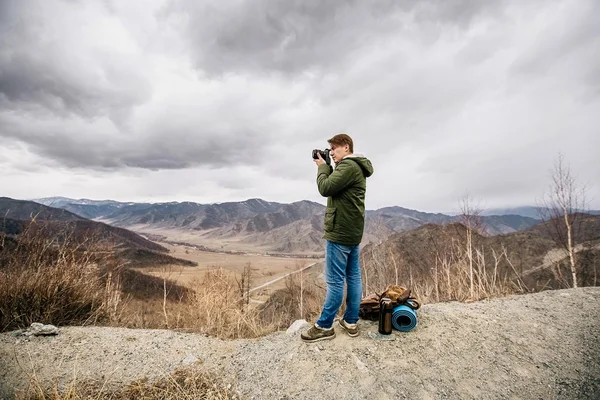 Человек с камерой останавливается на фоне гор — стоковое фото