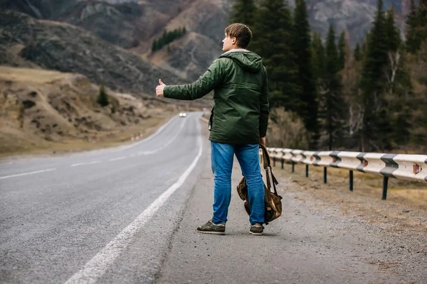 Un hombre viaja haciendo autostop en las montañas — Foto de Stock