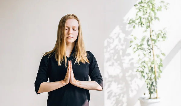Ung blond flicka i ett vitt rum gör meditation — Stockfoto
