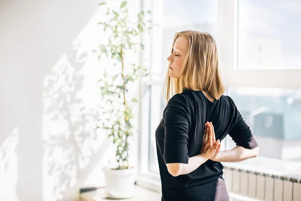 Ung blond flicka nära fönstret gör meditation — Stockfoto