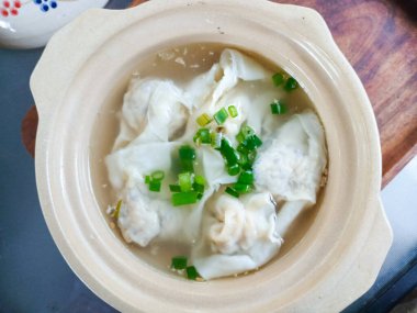 Taze ve temiz bir et suyuyla birlikte kilden bir tencerede servis edilen temiz bir Asya wonton çorbası. Mutfak kavramları, restoranlar ve geleneksel yemekler için mükemmel..