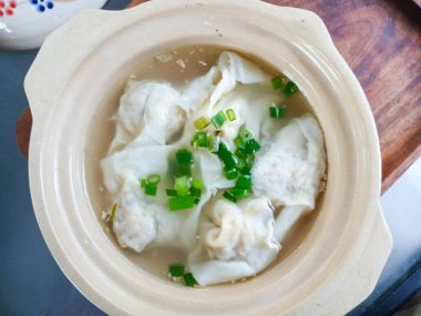 Taze ve temiz bir et suyuyla birlikte kilden bir tencerede servis edilen temiz bir Asya wonton çorbası. Mutfak kavramları, restoranlar ve geleneksel yemekler için mükemmel..