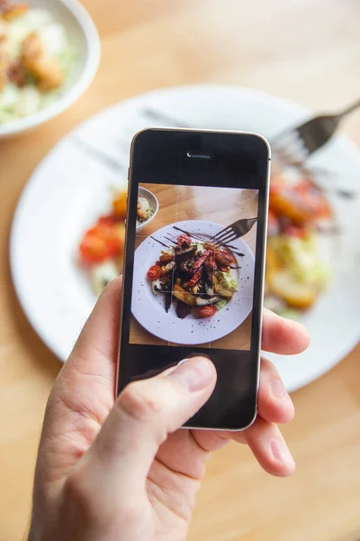 stock image A man photographs a delicious salad on his phone in a restaurant