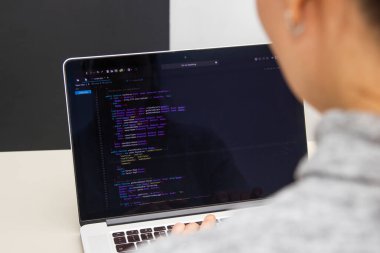 İşyerindeki bir dizüstü bilgisayarda kodlama yapan bir programcı