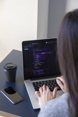İşyerindeki bir dizüstü bilgisayarda kodlama yapan bir programcı