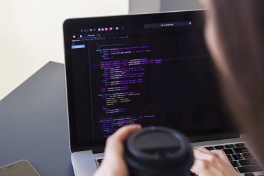 İşyerindeki bir dizüstü bilgisayarda kodlama yapan bir programcı
