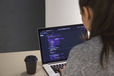 İşyerindeki bir dizüstü bilgisayarda kodlama yapan bir programcı