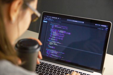İşyerindeki bir dizüstü bilgisayarda kodlama yapan bir programcı