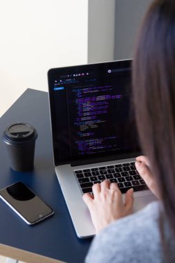 İşyerindeki bir dizüstü bilgisayarda kodlama yapan bir programcı
